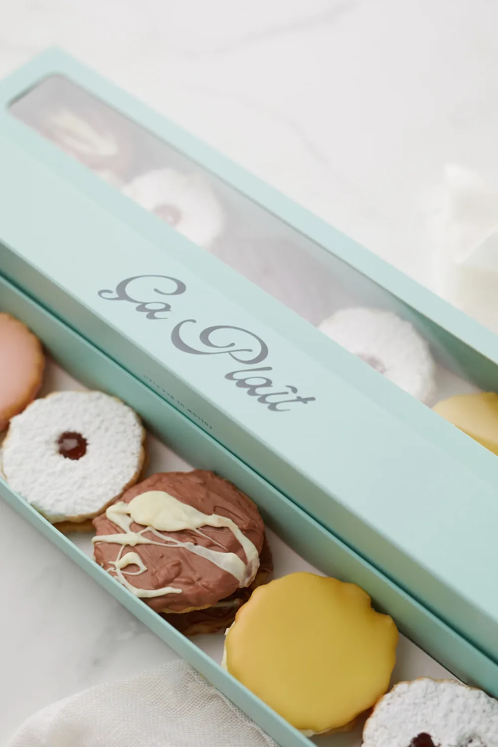 Ça Plaît biscuits in the brand’s mint box on white marble.