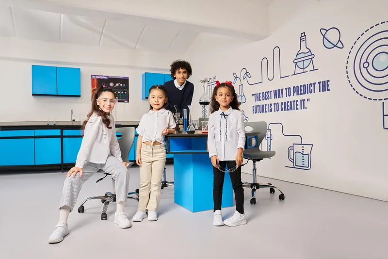 LC Waikiki Back to School 2025 campaign photograph: four students in a classroom in front of a blue wall and a hand-drawn science mural.