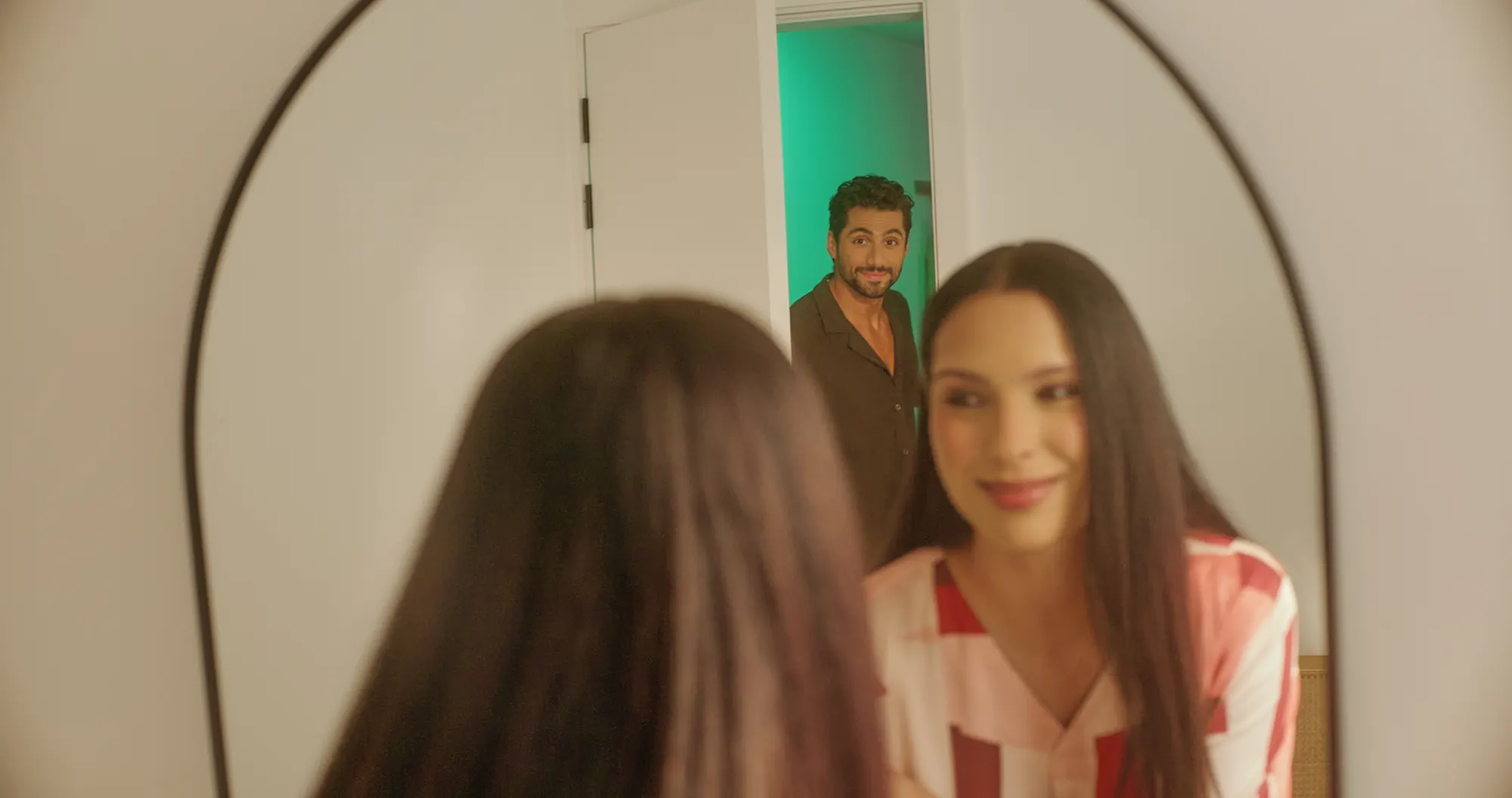 A still from the LC Waikiki Ramadan and Eid 2026 film: a woman smiling into a mirror at home.