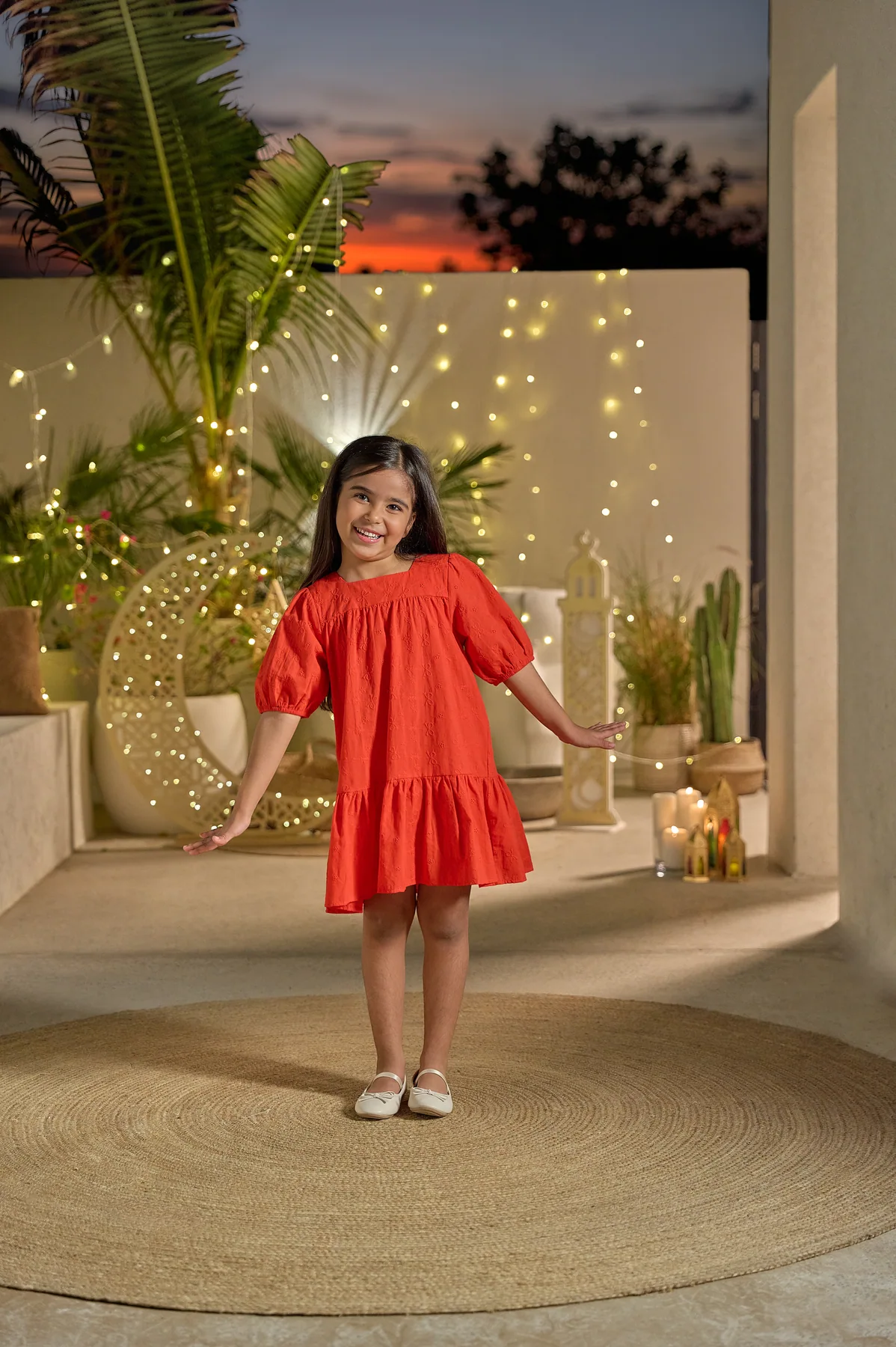 LC Waikiki Ramadan and Eid 2026 campaign photograph: a girl in a red dress on a terrace lit for the season.