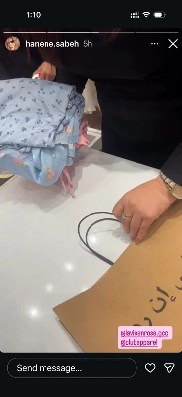 A La Vie en Rose purchase being packed at the store counter: folded blue pyjamas beside a paper shopping bag.