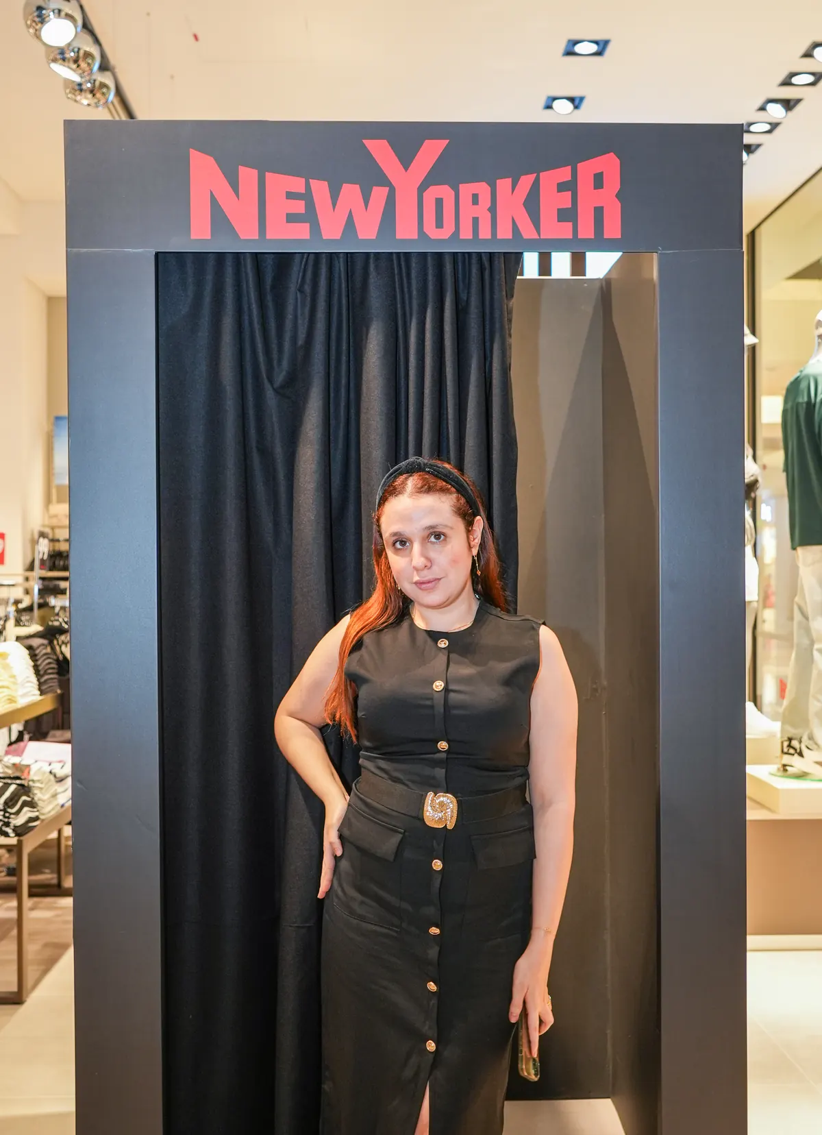 A guest in front of the branded NEW YORKER booth at the Reem Mall opening, its curtain closed.