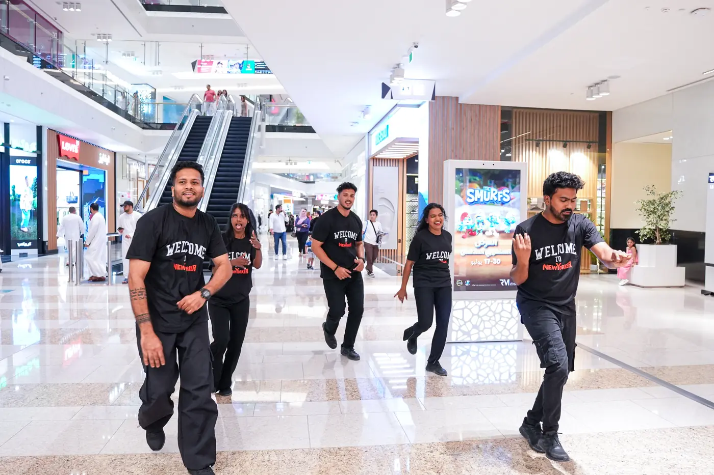 Performers in NEW YORKER Welcome T-shirts dancing through Reem Mall towards the store on opening day.