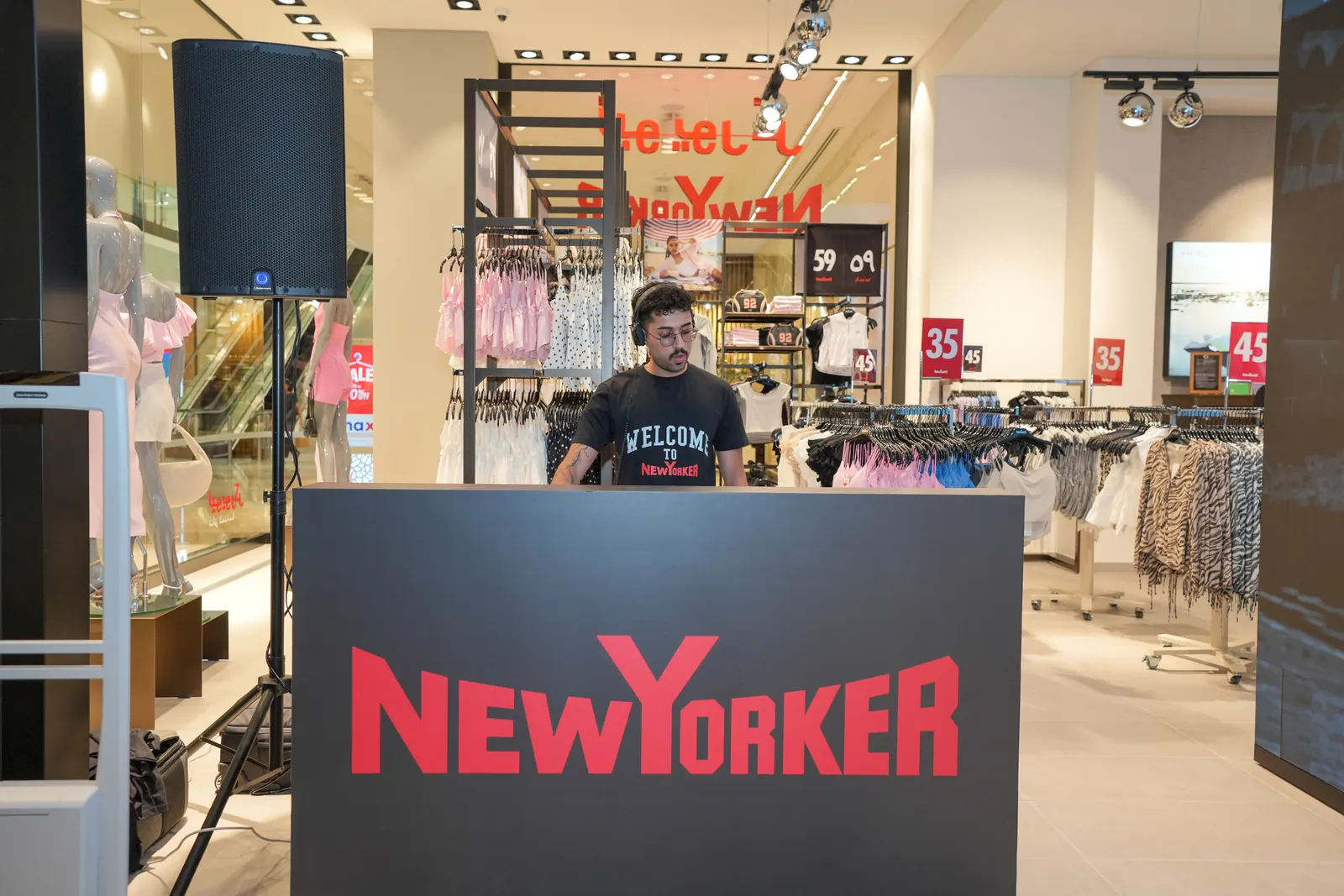 The branded NEW YORKER DJ booth at the Reem Mall store opening, with the DJ playing in a Welcome T-shirt.
