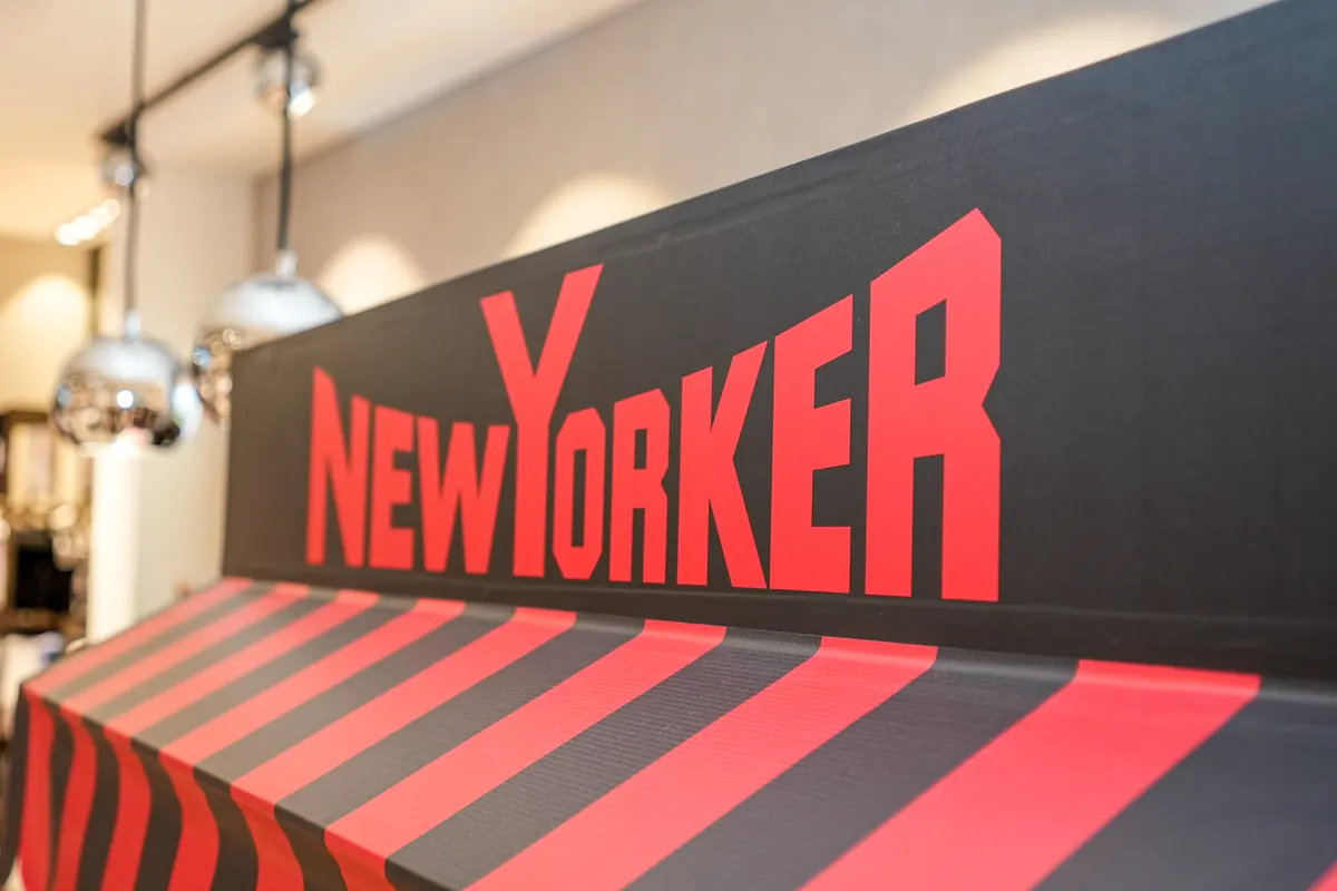 The NEW YORKER logo on the DJ booth fascia, with red and black stripes.