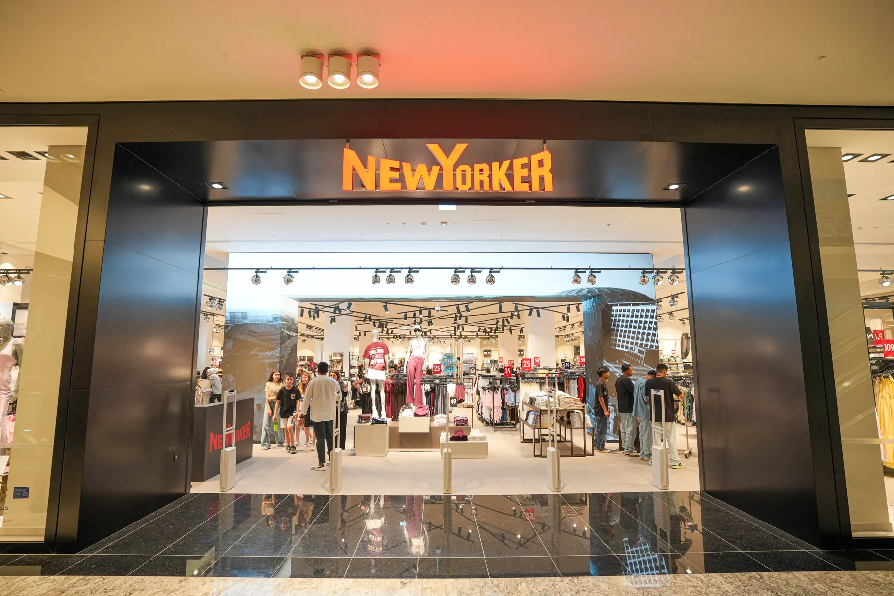 The NEW YORKER store entrance at Reem Mall on opening day, its illuminated sign above the doors.