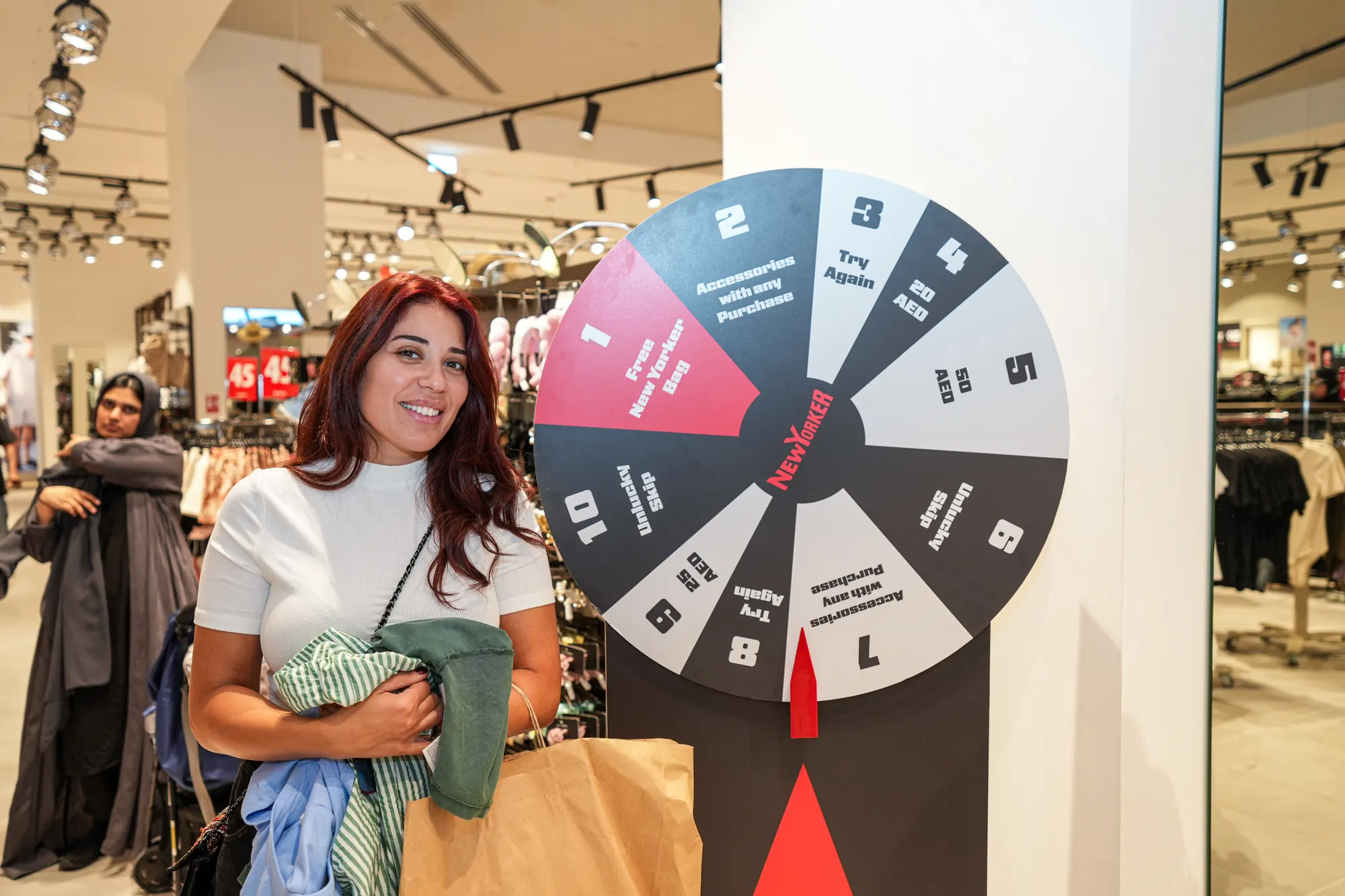 A guest with her shopping beside the NEW YORKER spin-the-wheel stand.