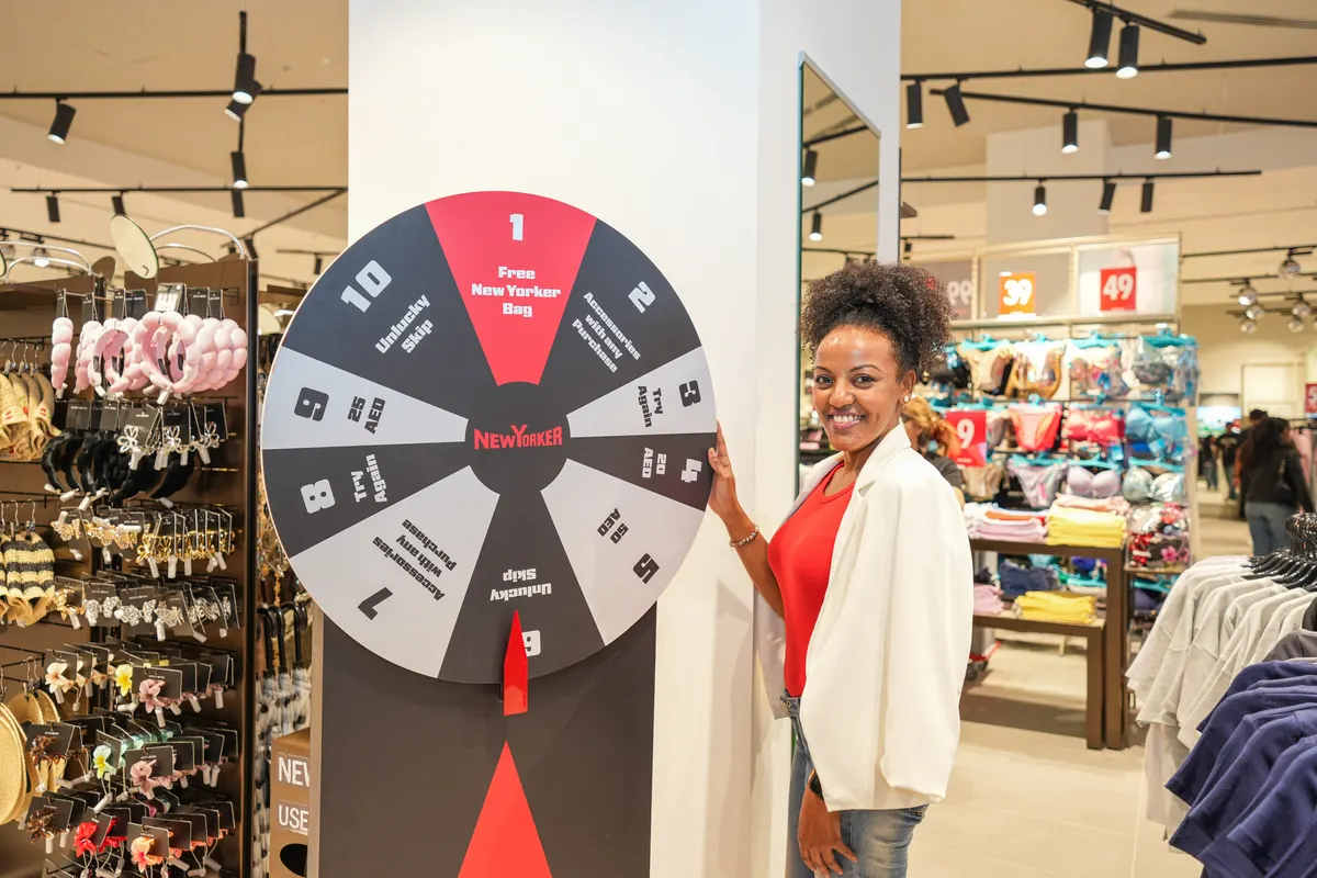 A guest smiling beside the NEW YORKER spin-the-wheel stand.